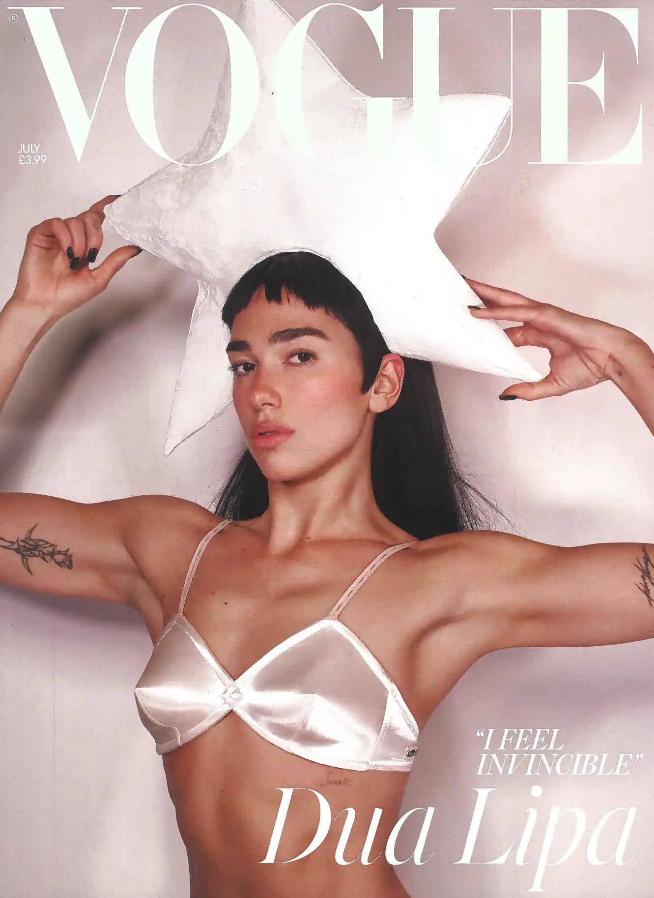 Dua Lipa on the cover of Vogue magazine, wearing a white star-shaped hat and a satin bralette.