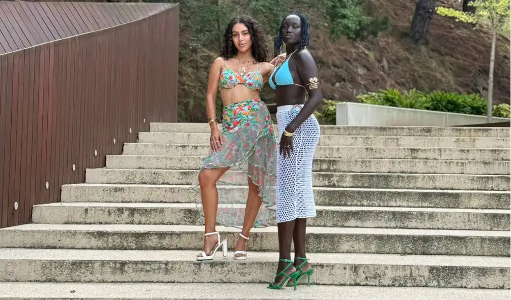 Two women modeling summer outfits on a staircase.