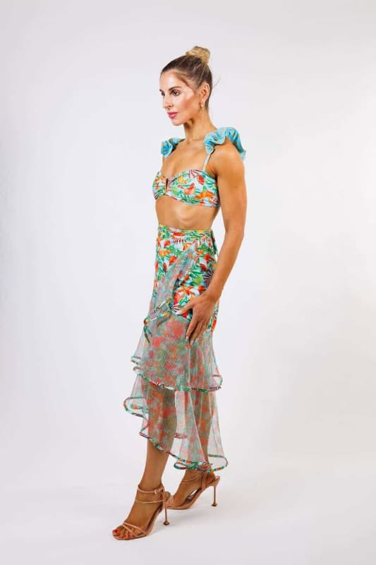 The model is wearing the Sofia Wrap Skirt by Zinzina Swimwear, which is styled for luxury coastal escapes.